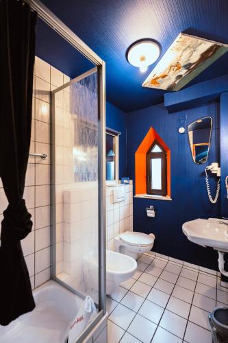 a blue bathroom with a shower and a toilet at Design Hotel Euskirchen in Euskirchen