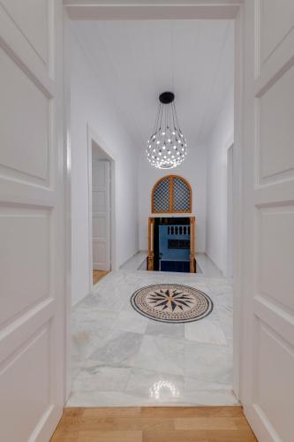 a hallway with a white room with a chandelier at White Loft Syros in Ermoupoli