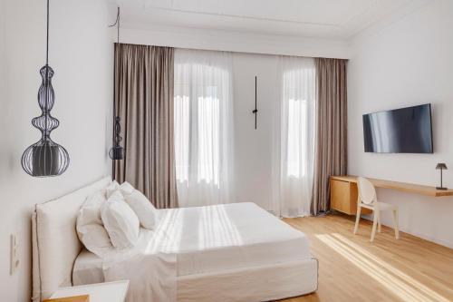 a white bedroom with a bed and a tv at White Loft Syros in Ermoupoli