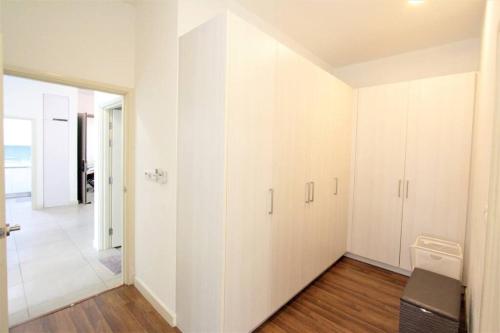 an empty living room with white walls and wood floors at Afiniti Residensi Legoland Medini in Nusajaya