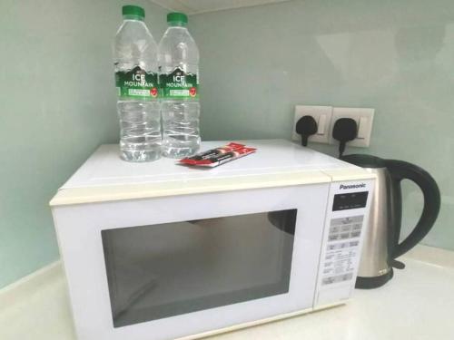 two bottles of water sitting on top of a microwave at Afiniti Residensi Legoland Medini in Nusajaya