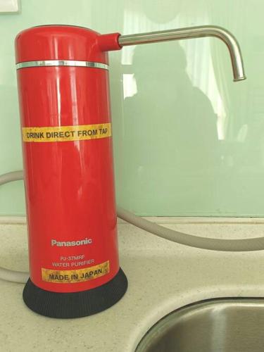 a red thermos sitting on a counter next to a sink at Afiniti Residensi Legoland Medini in Nusajaya