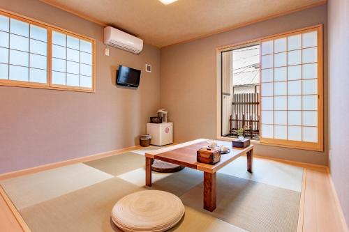 a living room with a table and two windows at Kyoto KaedeHotel Kamogawa in Shimmachidōri