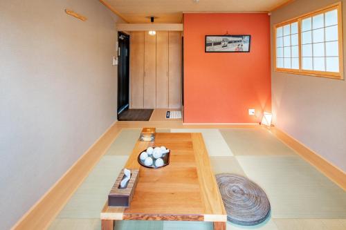 a living room with orange walls and a wooden table at Kyoto KaedeHotel Kamogawa in Kyoto