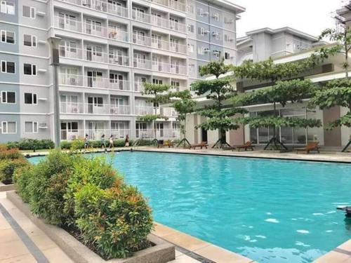 a swimming pool in front of a large building at Condo unit up to 10 pax - with Netflix and Boardgames in Manila