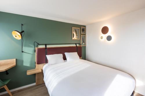 une chambre avec un lit blanc et un mur vert dans l'établissement Campanile La Rochelle Nord - Puilboreau Chagnolet, à Puilboreau
