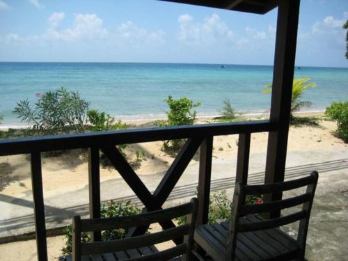 een balkon met een stoel en uitzicht op het strand bij Dumba Bay Tioman in Tioman Island