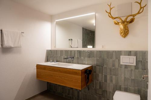 baño con lavabo y cabeza de ciervo en la pared en Balmas Paradies-perfect family home, en Zermatt