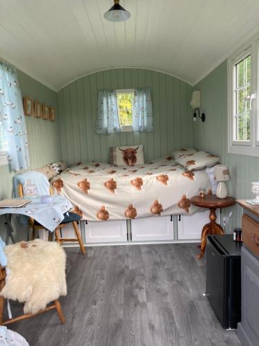 1 dormitorio con 1 cama, mesa y sillas en Bells Meadow Shepherds Hut, en Kings Lynn