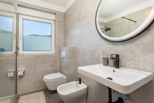 a bathroom with a sink and a toilet and a mirror at Pool Apartment Maurina Opatija with sea view in Ičići