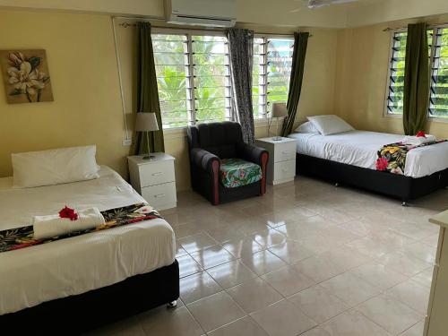 a bedroom with two beds and a chair in it at Libby's Vacation Rental 2 Bed Home 1-4 Guests in Nadi