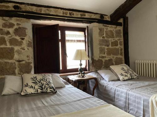 2 camas en una habitación con una pared de piedra en Casa familia La Casa de Quintanilla 2, en Aguilar de Campóo