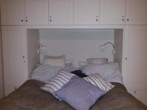 een slaapkamer met witte kasten en een bed met kussens bij Bergland apartment 15 - close to the center of Kragerø in Kragerø