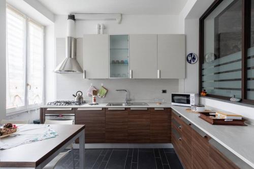 コモにあるMagnifico Appartamento Centro Comoの白いキャビネット、シンク、テーブル付きのキッチンが備わります。