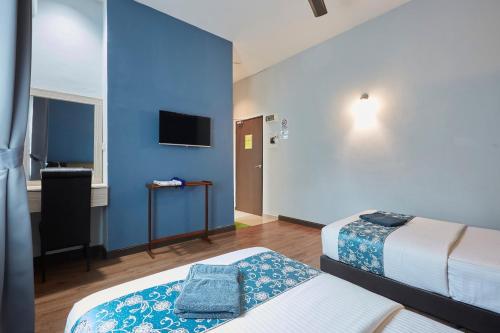 Habitación de hotel con 2 camas y pared azul en D' Qamar Guesthouse en Kuantan