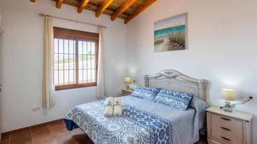 Casa Tortela Almáchar by Ruralidays في Almáchar: غرفة نوم عليها سرير وحذيين