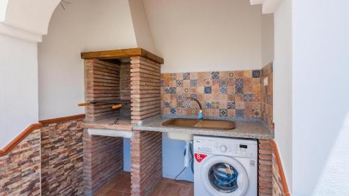 una lavadora y secadora en una pequeña cocina con fregadero en Casa Tortela Almáchar by Ruralidays en Almáchar