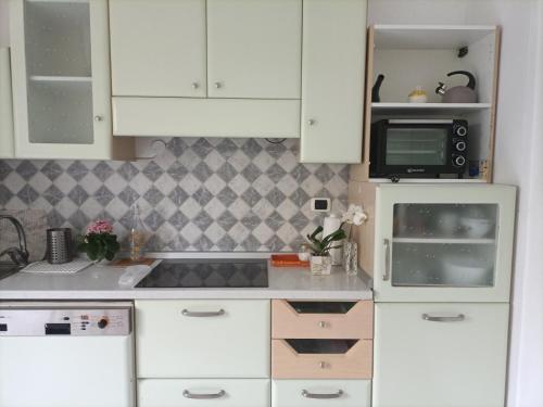 una cucina con armadietti bianchi e forno a microonde di Residenza Chiara a Forlì