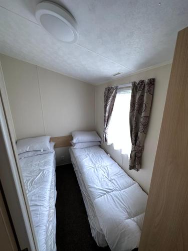 a small bedroom with two beds and a window at E11 Sunnymede Ingoldmells Lee's holiday homes in Skegness