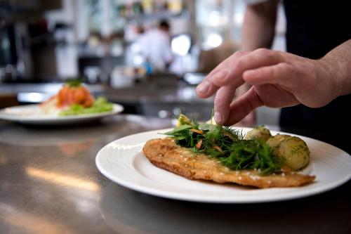 a person is eating a piece of fish on a plate at Golf Hotel Viborg in Viborg