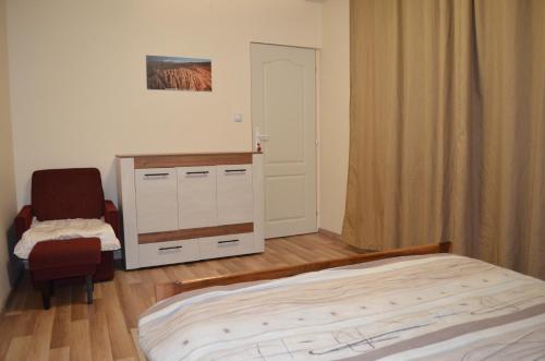 a bedroom with a bed and a chair and a cabinet at Villa Bella - A Rila Monastery Adventure in Kocherinovo