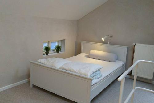 een wit bed in een kamer met 2 ramen bij Hus-lejlighed i ejendommens baghus in Odense