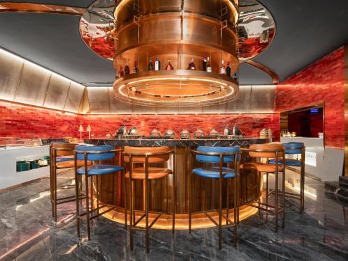 a restaurant with a bar with blue stools at Echarm PLUS International Hotel Zhujiang New Town Wuyangcun Metro Station Branch- Free Deliver Service to Canton Fair Complex During Canton Fair Period in Guangzhou