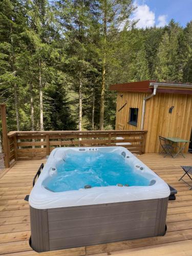 a hot tub sitting on a deck next to a cabin at Le Refuge perché du saut de la bourrique SPA, terrain clôturé Gérardmer in Gérardmer
