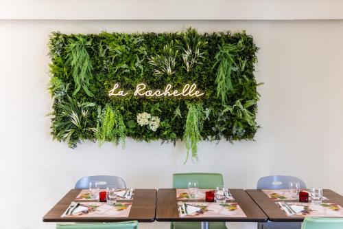ピュイルボローにあるCampanile La Rochelle Nord - Puilboreau Chagnoletのダイニングルーム(テーブル2台、壁に看板付)