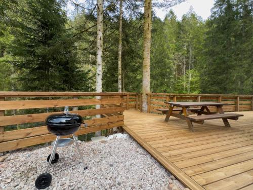 a wooden deck with a grill and a picnic table at Le Refuge perché du saut de la bourrique SPA, terrain clôturé Gérardmer in Gérardmer