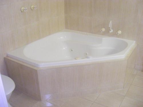 a white bath tub in a bathroom with a toilet at Weeroona Bed And Breakfast in Rye