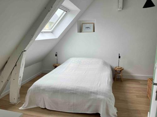 1 dormitorio con 1 cama blanca en el ático en La Petite Baleine, appt à 50m de la plage, en Luc-sur-Mer