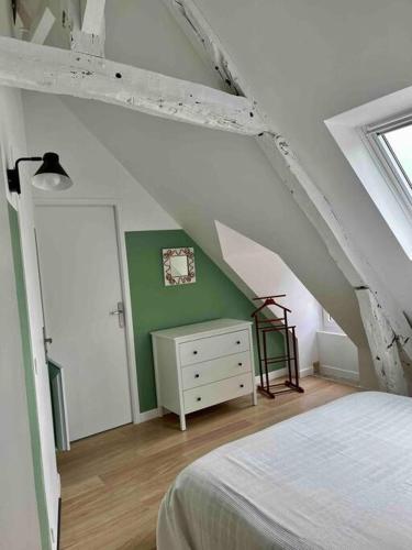 une chambre avec un lit blanc et un mur vert dans l'établissement La Petite Baleine, appt à 50m de la plage, à Luc-sur-Mer