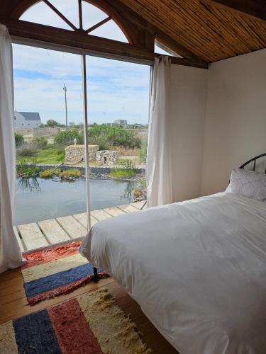 a bedroom with a bed and a large window at Aintree Lodge - Yoga Den in Langebaan