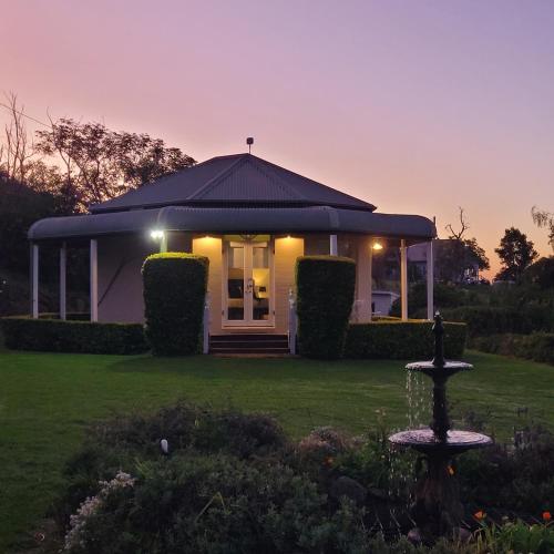 a house with a fountain in front of a yard at Mistress Block Vineyard in Pokolbin