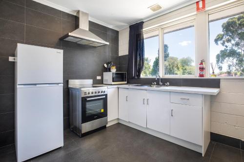 a kitchen with white cabinets and a white refrigerator at The Mulgrave Motel in Mulgrave