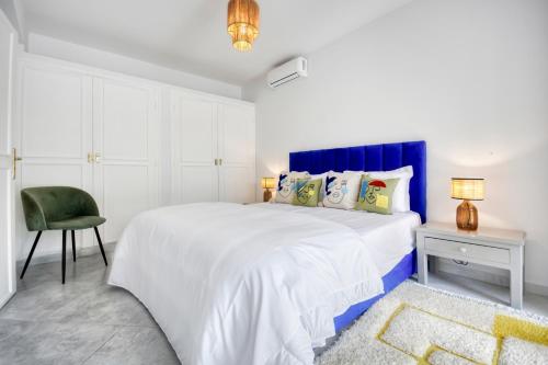a white bedroom with a large bed and a chair at Signature Agadir Villa Luxe for 4 or 6 PX in Agadir