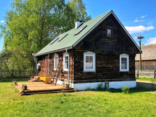 een klein houten huis met een veranda en een terras bij Magiczne Podlasie 