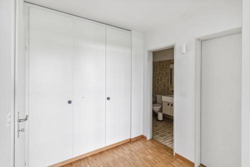 um quarto com paredes brancas e portas de correr em Beautiful Boutique Apartment DRAHTZUG16 em Zürich