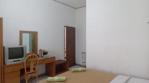 a bedroom with a desk with a tv and a chair at Hotel Asia Bukittinggi in Bukittinggi