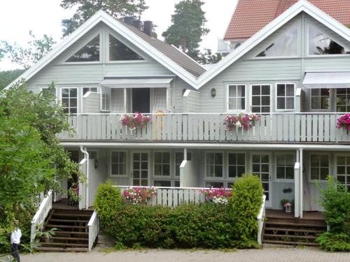 a white house with a balcony with flowers on it at Bergland apartment 18 - close to the center of Kragerø in Kragerø