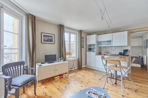 Il comprend un salon avec un bureau et des chaises ainsi qu'une cuisine. dans l'établissement Le Trianon - Appt à 100m de la plage, à Trouville-sur-Mer