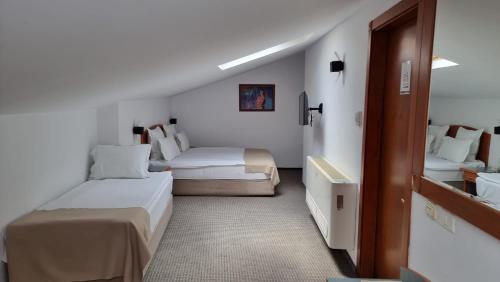 a hotel room with two beds and a bathroom at Hotel Duke Romana in Bucharest