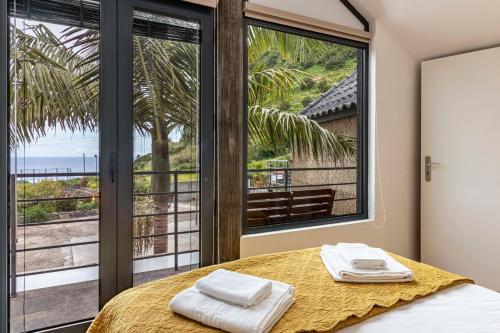 a bedroom with a bed and a large window at Cork House - Fernandes Cottage in Ponta Delgada