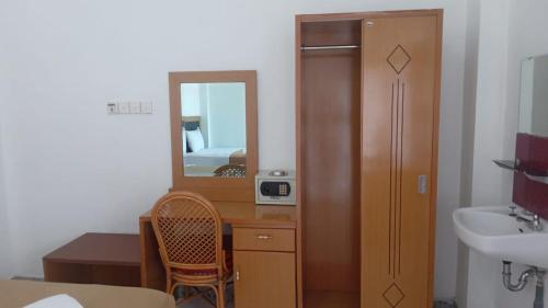 a bathroom with a sink and a desk with a mirror at Hotel Asia Bukittinggi in Bukittinggi