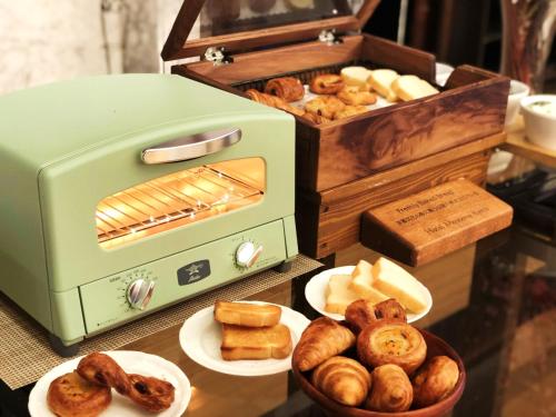 a green toaster sitting on a table with plates of bread at Hotel Monterey Kyoto in Kyoto