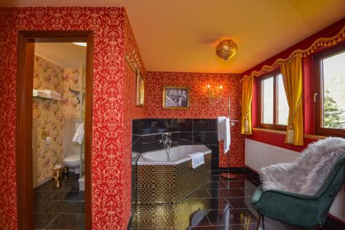 Łazienka z czerwonymi ścianami, wanną i umywalką w obiekcie Riverdam w mieście Ilmenau