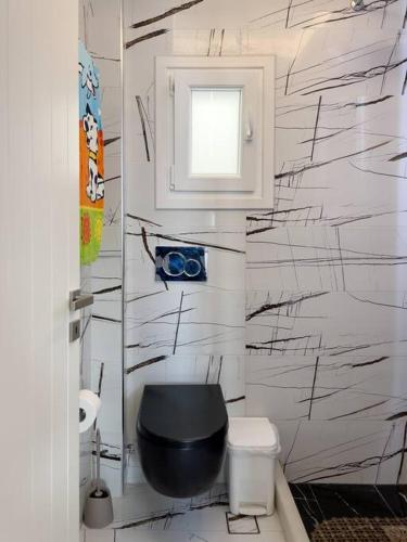 a bathroom with a black toilet and a window at Naxian Downtown Residence in Naxos Chora