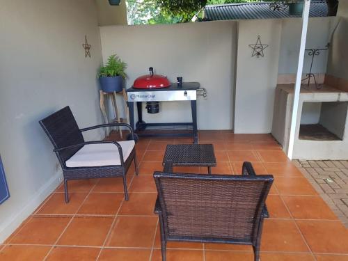 eine Terrasse mit Stühlen, einem Tisch und einem Herd in der Unterkunft Seba Cottages Mokopane in Mokopane