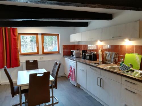 a kitchen with white cabinets and a table and chairs at Die Oberlochmühle PENSION in Deutschneudorf